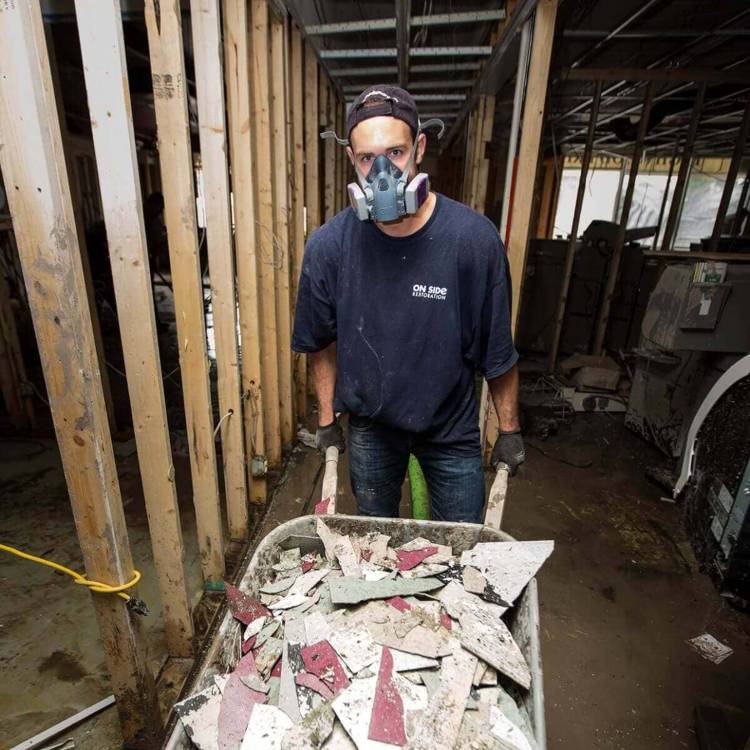 Man carrying broken tiles of current home restoration in Canada